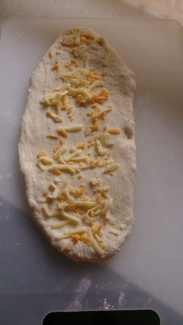 取出麵團將麵糰桿成長橢圓形，鋪上起司條和素火腿。