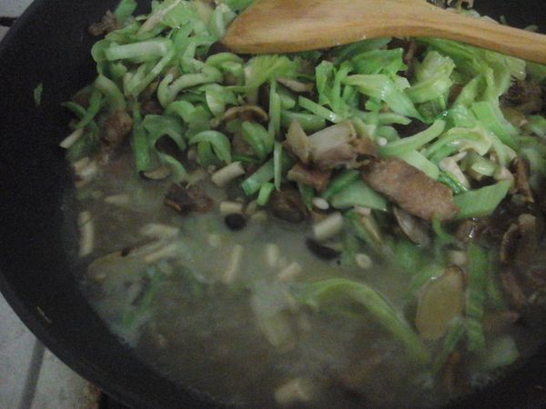 加入2量杯水和香菇水，接著把煮好的飯加入，開中火烹炒