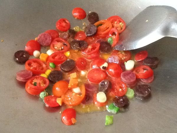 起鍋，開小火，加少許油，放入蕃茄、臘腸、蔥白與綜合蔬菜，先炒香與炒出茄紅素，完成先起鍋。