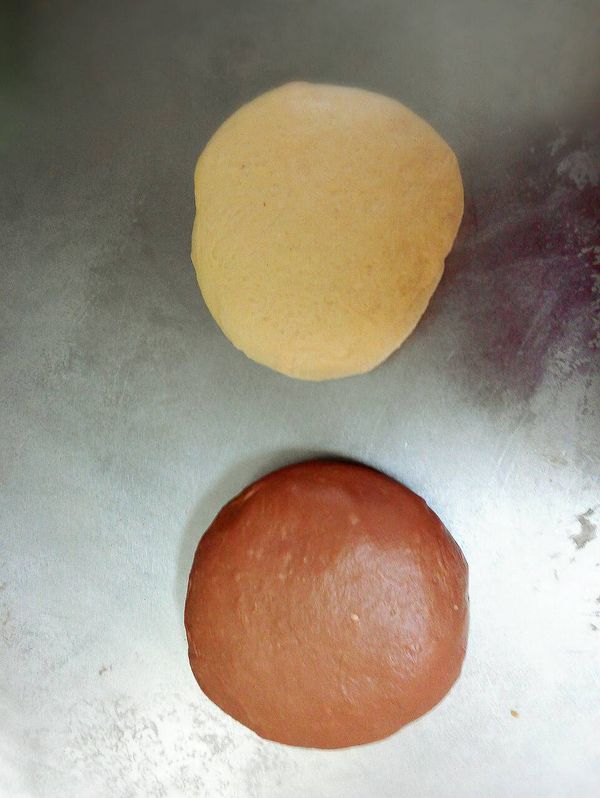 將兩個小麵糰分別加入巧克力醬及白芝麻醬,變成一黑一白的兩個麵糰,並繼續搓揉小麵糰變成兩個可以撐得起薄膜的麵糰