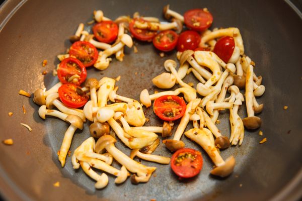 接著將蕈菇下鍋炒香後，再倒入番茄一起拌炒。