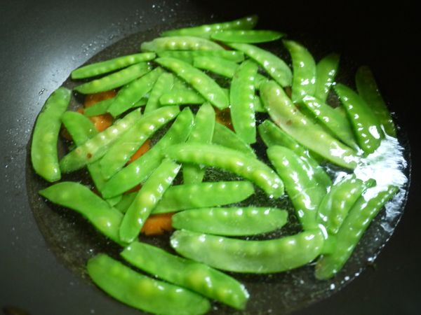 炒鍋加入適量的水再加入一大匙的油，水滾後加入胡蘿蔔片.荷蘭豆燙到半熟撈起