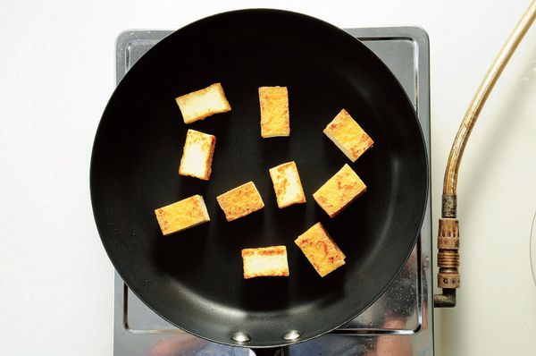 厚片油豆腐汆燙後對半直切成1cm厚，將厚片油豆腐放入鍋中煎至兩面上色。