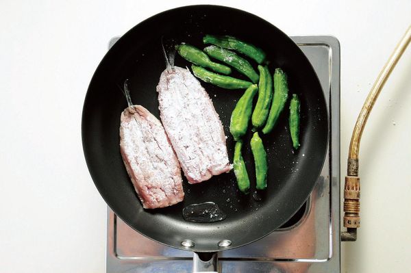 將油倒入平底鍋中以中火加熱，放入沙丁魚油煎。一旁順便油煎角椒，等角椒熟了先盛出備用。