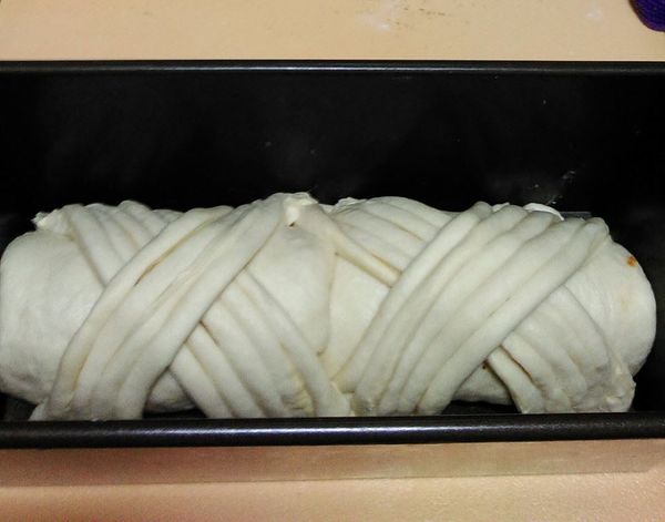 一發後取1/4麵糰,其餘分2個大麵糰滾圓鬆弛15分，大麵糰桿長方形包肉鬆及些許沙拉醬,由上往下捲,放吐司膜,另1/4麵團桿平上放酥皮,3桿3折,切長條,分4份，放上吐司麵糰上,進烤箱二發1小時