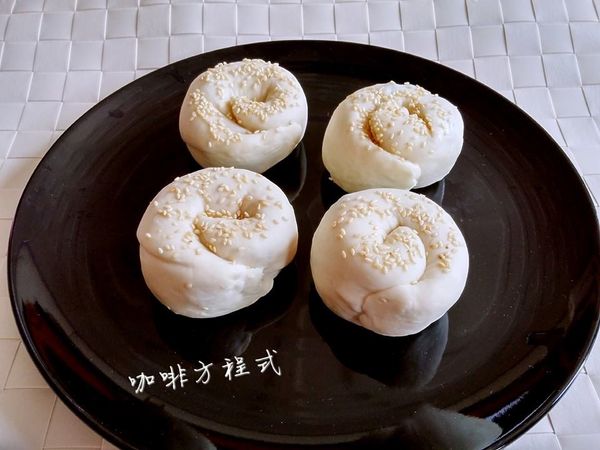 把麵糰分成8等份，取1個麵糰來桿平，抹上油、灑上蔥、胡椒粉，再慢慢的捲上來，圍成一個蝸牛形狀，上面灑些白芝麻