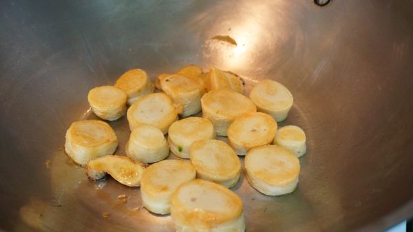 小火熱鍋後，倒入2茶匙麻油並爆香薑片，再將麵腸煎至表面金黃。不建議用中火或大火爆香，因為麻油不耐高溫，容易變劣質、發出苦味。