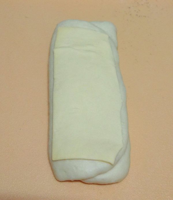 一發後分2大麵糰滾圓鬆弛15分，每個麵糰桿長方形，鋪1/2片酥皮,麵團三折再桿長方形，再鋪1/2片酥皮(如圖),(重複不用再加酥皮)4-5次後桿成大長方形，由左至右捲呈長條形,切割5等份,層次面朝上,進行二發1小時