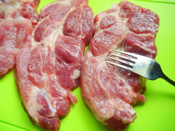 將梅花肉片使用叉子叉洞，可以讓肉片醃漬時吸滿肉汁且將部份肉筋斷除