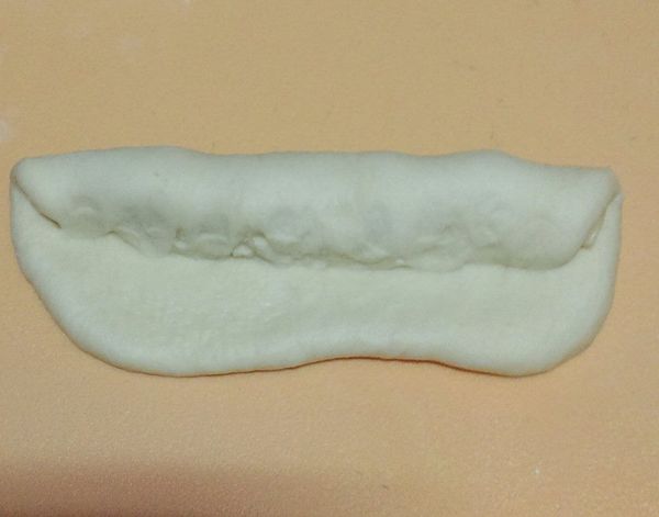 一發後分4小麵糰滾圓鬆弛15分，再每個麵糰桿長方形，舖上２小片起士，捲長橢圓型，中間切ㄧ較深的刀，進行二發50分鐘