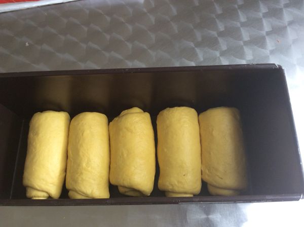 按扁後擀成楕圓片，捲起後再擀捲一次，擀成與土司模寬度等長的卷。排入模型中，蓋上蓋，發至模型的9分滿即可烘烤。350°F烤約30-35分鐘。