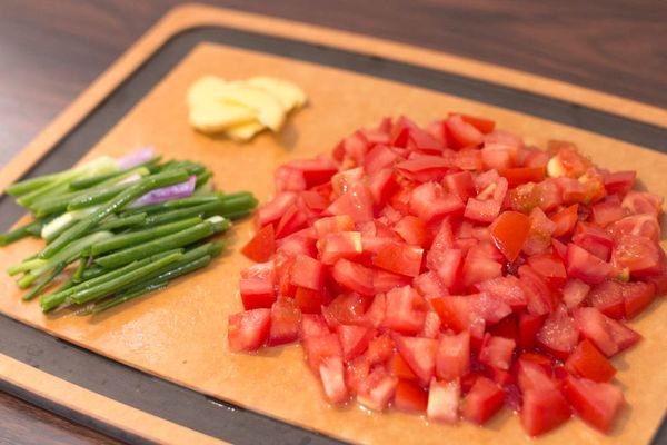 蕃茄洗淨去頭切約 1.5 cm 大小方粒，蔥洗淨去頭切約 1.5 吋段，薑切出 2 片