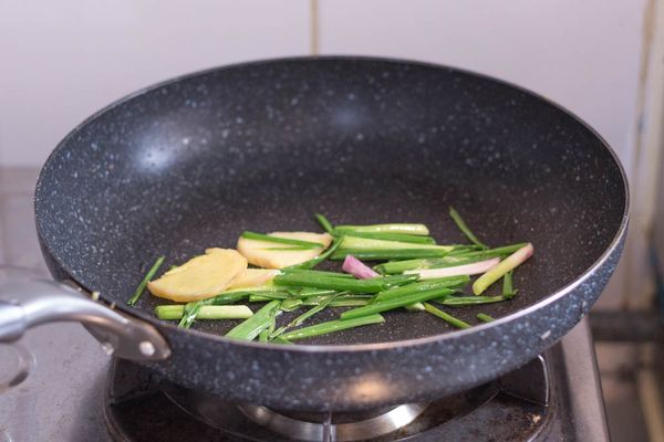 抹乾淨鍋子，開中火，下少許油，油熱後下薑片及蔥段炒大約1 - 2 分鐘至有香味