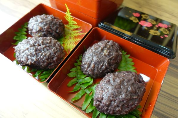 將紅豆泥放在手掌上，放入飯糰沾裹紅豆泥。如果紅豆泥太過濕潤黏稠，可以放乾一點或用鍋收乾些之後再將飯糰包入。