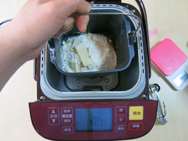 將製麵包容器提起裝入機器裡。