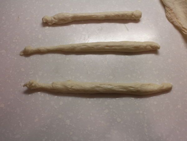 把鬆弛完的小麵團搓成約15cm長條狀。祕訣是兩手手掌一起在桌上搓揉，很容易就會搓成長條。