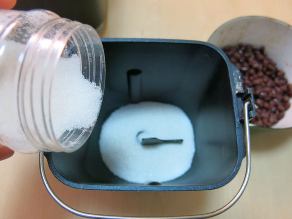 把戲砂糖慢慢倒入麵包機內鍋裡。