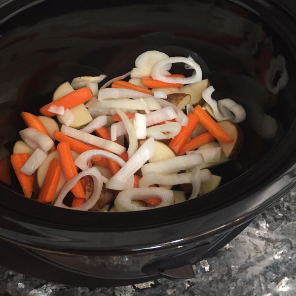 把馬鈴薯、洋蔥和胡蘿蔔切小塊後放進慢燉鍋裡。
