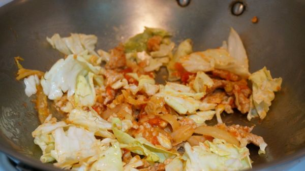 準備一鍋水，將義大利麵煮至8分熟。同時熱鍋後倒入3茶匙橄欖油，先將5顆蒜末和洋蔥爆香，再放入醃製好的豬肉片和豬絞肉，豬肉炒熟後再把整粒番茄罐頭倒入一起拌炒，最後放入高麗菜。高麗菜不要炒太久，醬汁有依附在上面就好。接者馬上放入義大利麵囉!