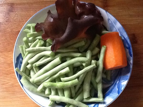 準備材料，乾木耳先泡水泡軟；四季豆去頭尾及老絲，折斷；紅蘿蔔削皮，完成後洗淨。