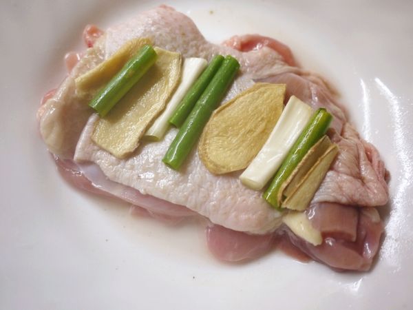 取一盤放入去骨雞腿或雞胸,抺上米酒及塩,再將葱段及薑片鋪於上放入電鍋,以1米杯水蒸熟