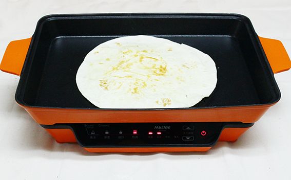 將墨西哥薄餅煎到二面微焦，鋪上一些起士絲，對折再對折，先擺在盤子上備用。