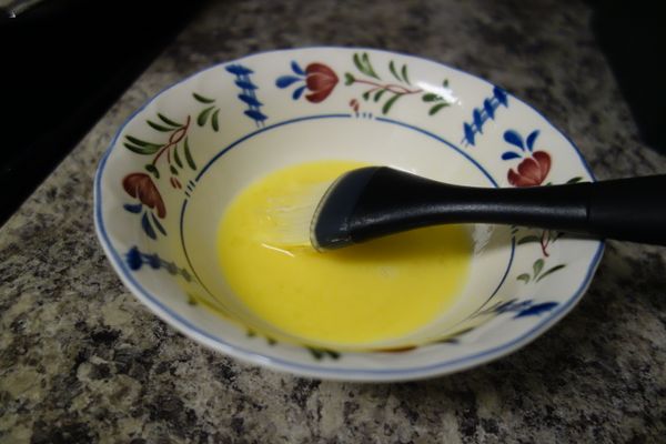 拿掉烤盤紙和重物，在烤過的派皮上均勻刷上一層蛋液