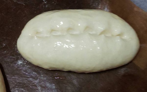 一發後分8小麵糰滾圓鬆弛15分，再每個麵糰桿長方形，由上往下捲，進行二發1小時烤前每個麵糰表面切(剪)一深0.5公分長刀,刷蛋液,鮪魚玉米明太子醬攪拌,舖在中間切口