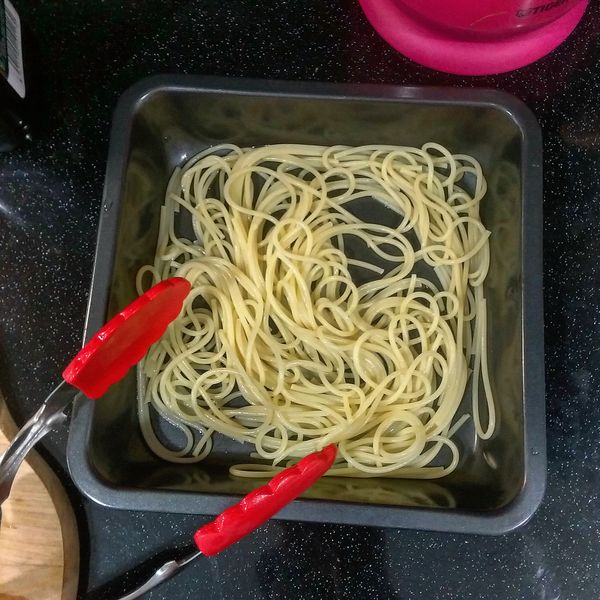 這時麵也差不多烹煮完成；取一容器，倒入少許橄欖油，再將煮好的麵瀝乾放入，攪或攪或，這樣麵條就不會沾黏打結，放置一旁。