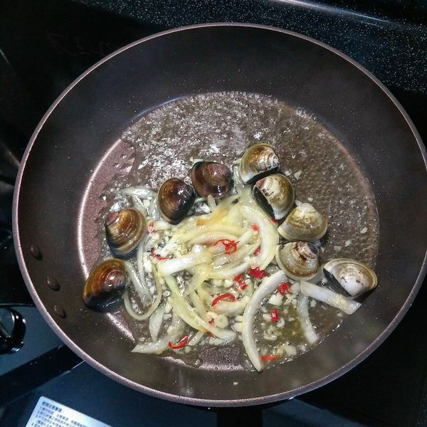 接續步驟(5)；加入蒜末及辣椒(勿炒焦)，適度離火炒至大蒜香氣出來即可；接續加入白酒、蛤蜊及九層塔，酌量加入鹽，蓋上鍋蓋(重要)，以中大火烹煮，讓酒精揮發掉。