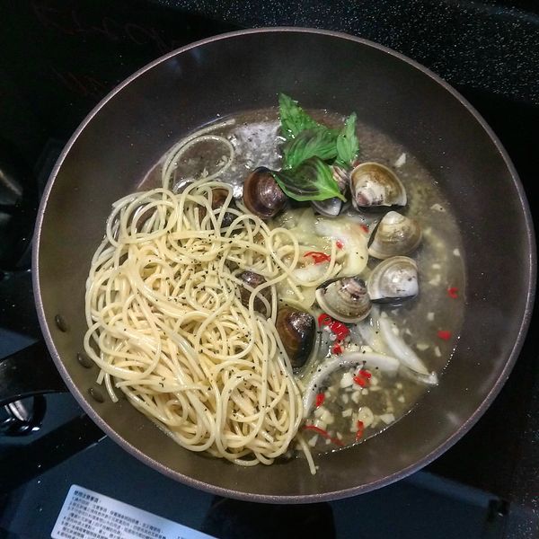 接續步驟(6)；蛤蜊半開後加入煮好的麵條及奶油，拌炒至蛤蜊全開並稍微收汁即可盛盤；盛盤時再灑上些九層塔末，完成。