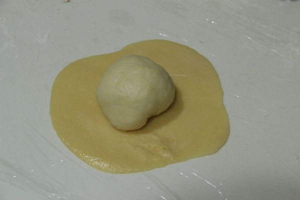 將 [菠蘿皮] 放在桿壓成圓形，然後把剛剛的麵包麵糰放在 [菠蘿皮] 上