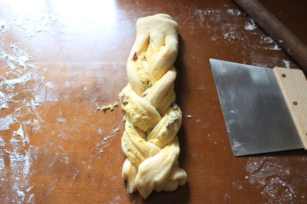 接著編成辮子形狀，尾端壓緊後，兩端由下方往中間收。