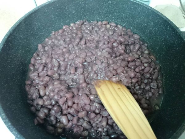 煮好的紅豆粒倒入炒鍋中，多餘的紅豆水可倒出喝掉。