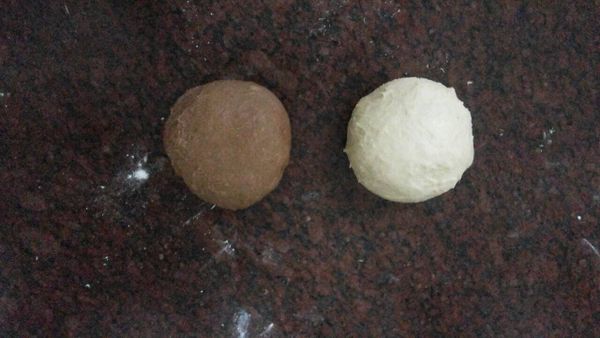 完成第一次發酵後,將麵糰取出,灑先麵粉,並拍出多餘空,並將麵糰分成2份滾成圓形,蓋上保鮮膜讓麵糰休息15分鐘後,將其中一份麵糰加入己調均勻的[B]並揉至成可可色.