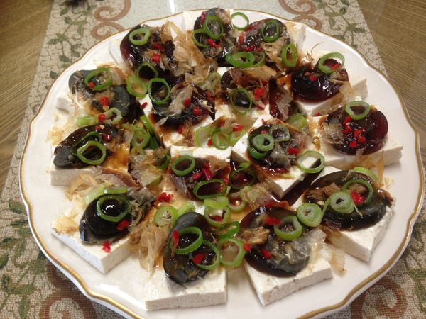 豆腐跟皮蛋擺好淋上醬汁，撒上柴魚片、蔥花跟辣椒末即可