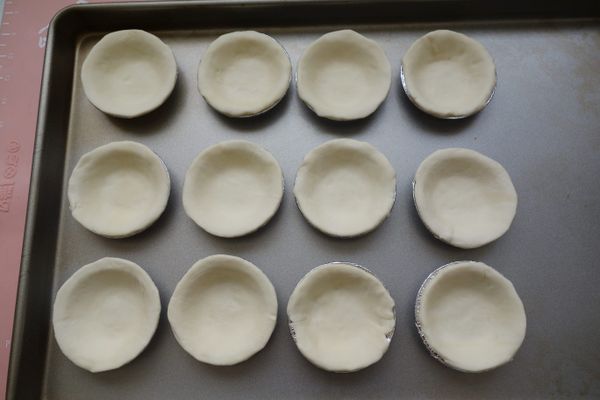 酥皮裁好放在蛋塔模上，用指尖輕壓讓酥皮服貼