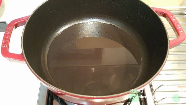 放少許水在鑄鐵鍋裡，開小火加熱至冒小泡泡後 > 分散平鋪一些蒜頭，我是挑大顆點的鋪（主要讓魚肉跟鍋子有個距離）。