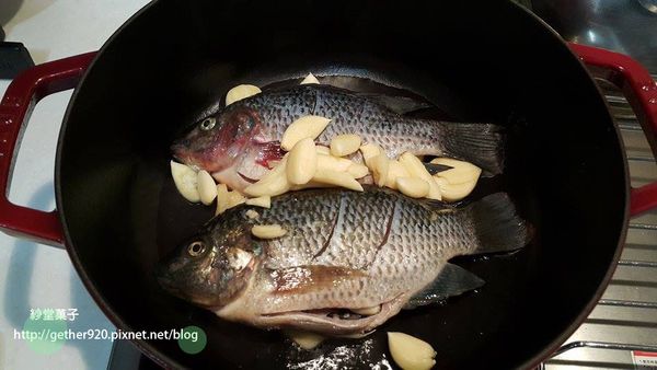 把魚放上鋪蒜頭的鍋內 > 剩餘的蒜頭鋪在魚上面。
