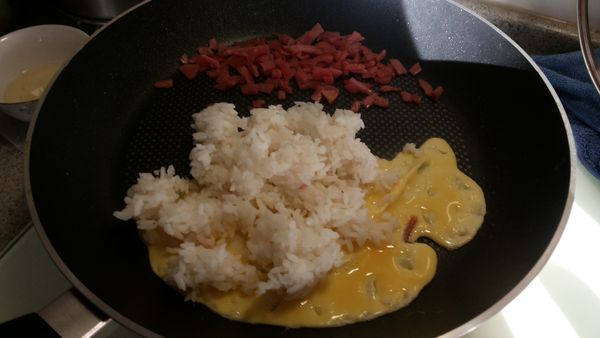 鍋邊先炒香火腿再倒入剩下蛋液,將飯也放上拌炒