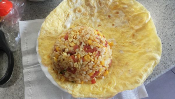 炒好的飯裝到碗,用飯匙稍按壓緊飯才不會散開…倒扣在蛋皮邊