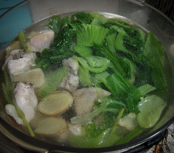 重新燒鍋熱水，將雞腿塊、薑片、葱段放入鍋內稍滾，再加入刈菜，略煮約10分鐘。