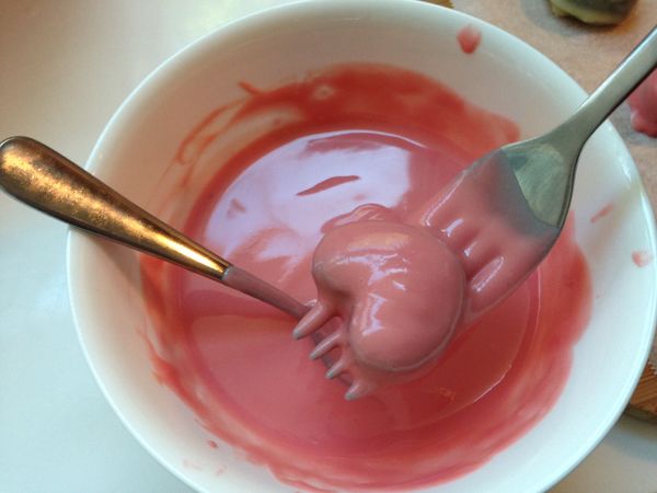 使用叉子承接冰涼的餅乾，淋上草莓巧克力後放烘焙紙上再次放進冰箱