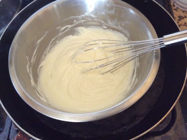在烤蛋糕的時候，準備芝士蛋糕的麵糊。[B]部分的奶油起司和糖隔熱水加熱，用打蛋器攪拌至光滑無顆粒。