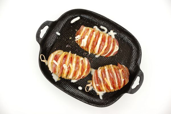 煎好的香腸切成片狀,以間隔方式依序將香腸片及乳酪絲塞入馬鈴薯裡。再送入烤箱烘烤至乳酪絲融化即完成。