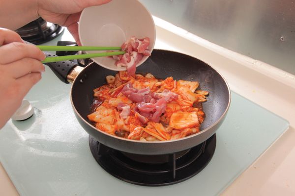 燒熱平底鑊，加入葡萄籽油，爆香蒜片，加入泡菜、肉片炒4分鐘。