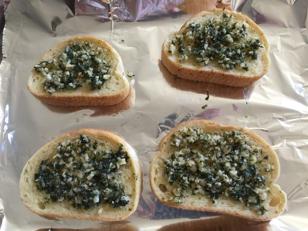 烤好的麵包出爐後，鋪上適量的大蒜奶油醬