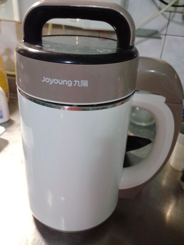 使用九陽豆漿機，放入洗淨的黃豆和黑芝麻，加入水，插電按[五穀]