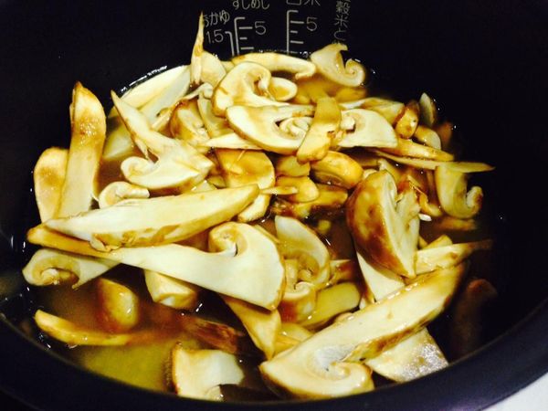 將米放進電鍋中,先將醬油、酒、剛剛醃松茸後殘留的醬油汁倒入量杯(量米的杯子)中再加滿昆布水拌勻倒入鍋中,最後加入剩下的昆布水至三杯米的水量處,鋪上醃好醬油的松茸(所以整個調味料加昆布水合在一起是三杯米所需的水量喔)