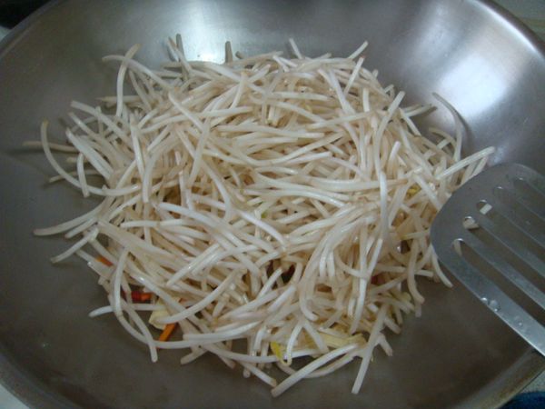 步驟3下豆皮.豆芽菜.拌炒約一分鐘.沿鍋邊嗆些米酒.水.再拌炒均勻.